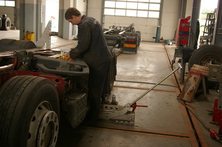 Darbininkas ruošia sunkvežimio važiuoklę remontui